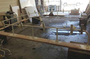 The metal rail attached to wood sitting on the ground in the shop. It will go around the edge of the boat