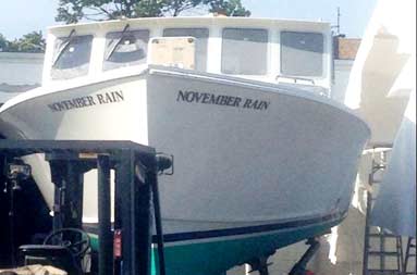 View from ground level looking slightly up at the front of the boat with the November Rain name painted on both sides