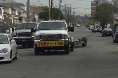 View of a pickup truck with the sign 'Wide Load' driving down the street to prepare for the boat move