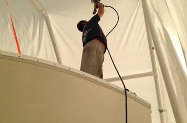 Joe, from Atlantic Service and Equipment were the boat is being worked on, uses a hand held dryer to smooth out the tent