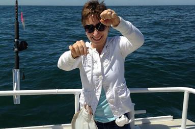 Anatasia on the boat holding up his her fluke on the line