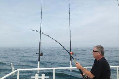 Bob sitting on the boat, out in the ocean, with his line in the water.