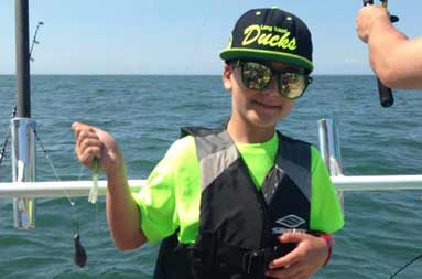 One of the kids holding up a fluke on the line.