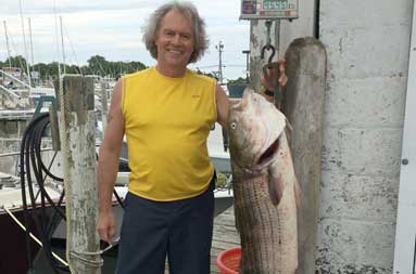 Ken standing next to the bass on the hanging scale at the marina