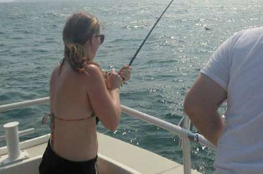 A girl on the trip reeling in a bass