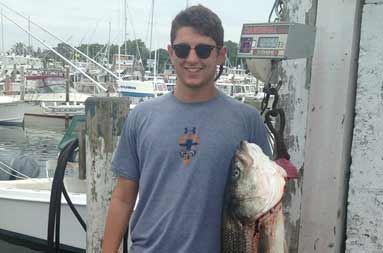 One of the guests smiles holding a 30 pound bass