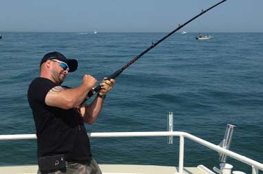 Another guy reeling a fish in from the water.