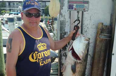 One of the guys back at the marina standing next to a 44+ lb bass hanging on the scale