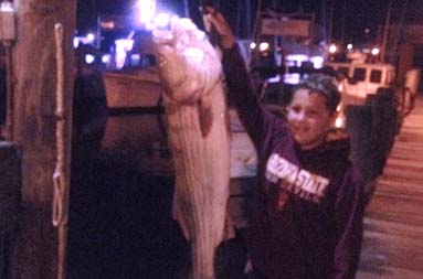 A night shot of Daniel standing next to his fish being weighed