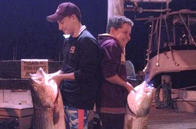 A night shot of the brothers standing back to back, each holding their catch
