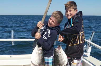 The two young boys each holding the bass they caught