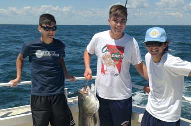 The three young guys posing for a photo on the boat