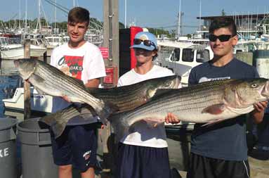 Three of the young guys back at the dock at the marina each holding their fish