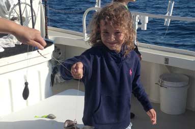 One of the little girls on the boats holding a fish attached to the line