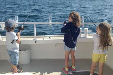 Three of the young kids all with rod and reel in hand fishing