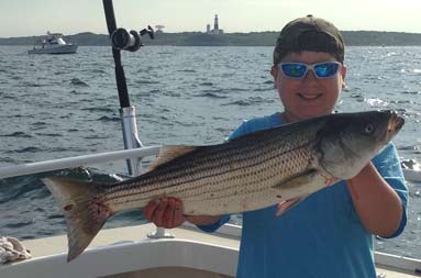 A young boy holding up his striped bass 