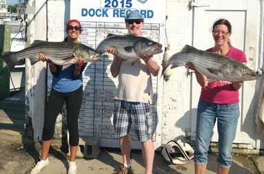 Three of the crew back at the marina, each holding their catch