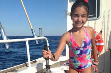 A young girl in her colorful bathing suit holding up the porgy she caught