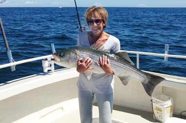 Capt. Jill's mom holding up the striped bass she caught