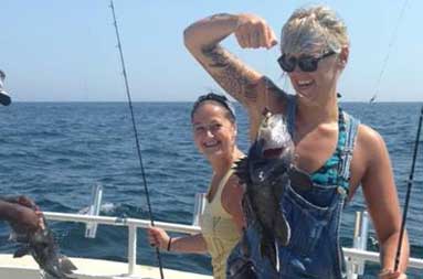 One of the women holding the reel with 2 fish caught on the line