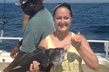 One of the women holding up the a sea bass she caught.