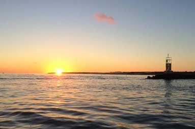 View from the boat of the sun setting over the water at the inlet