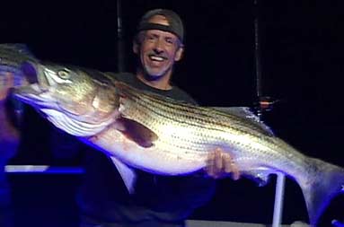 Night shot of Kevin Wish posing with his large bass.