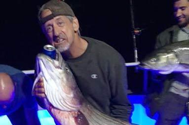 One of the guys holding up the bass he caught pretending to drink a beverage out of it's mouth