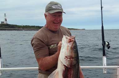 One of the men standing on the boat holding up a large bass