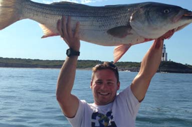 One of the younger guys holding a large bass over his head and smiling