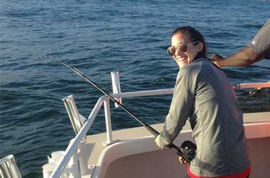 One of the women smiling back at the camera as she fights to reel in a fish