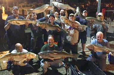 Night group shot back at the marina of everyone holding their catch
