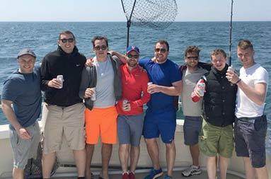 A group shot of everyone on deck with water behind them out at sea.