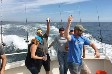 A group of men and women smiling and having a good time on the boat