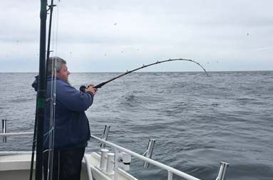 A man aboard the boat reeling in his line.