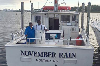View from the dock of First mate Gil standing next to one of the guests from the charters abroad the boat.