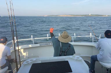 View from the door of the cockpit of first mate Gil on deck and the father and son with their lines in the water.