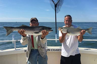 A man with his 75 year old father proudly hold up the fish they caught.