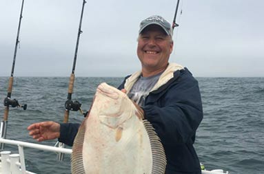 Another man holding up the fluke he caught.