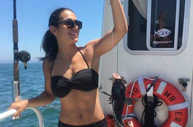 A woman proudly holds up the fish she caught.