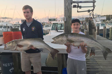 Back at the marina, two adolescent boys each hold up the fish they caught.