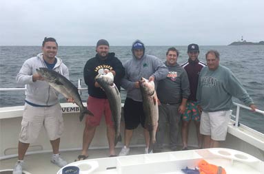 A group of 6 men each hold up the fish they caught.