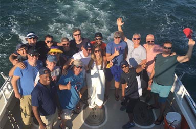 View from atop the boat looking down at a large group of men and women smiling for the camera.