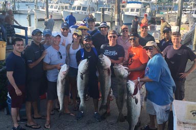 Back at the marina, the large group of men and women smile for the camera and hold up the fish they caught. /><span class=