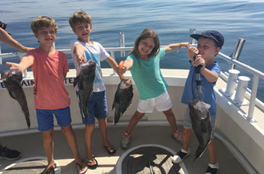 Three boys and a young girl each hold up the fish they caught.