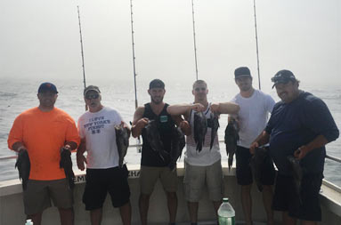 A group six men each hold up their catch.