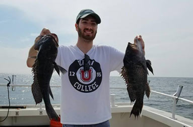 A man holds up two sea bass.