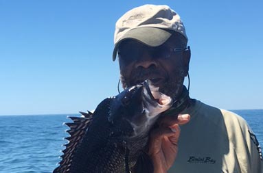 Close-up of a man holding up the sea bass he caught.