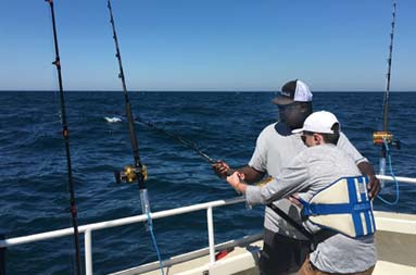 First Mate Gil helps out one of the guys on the boat as he tries to reel in a shark.