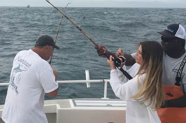 First mate, Gil, helps Sarah reel in a fish